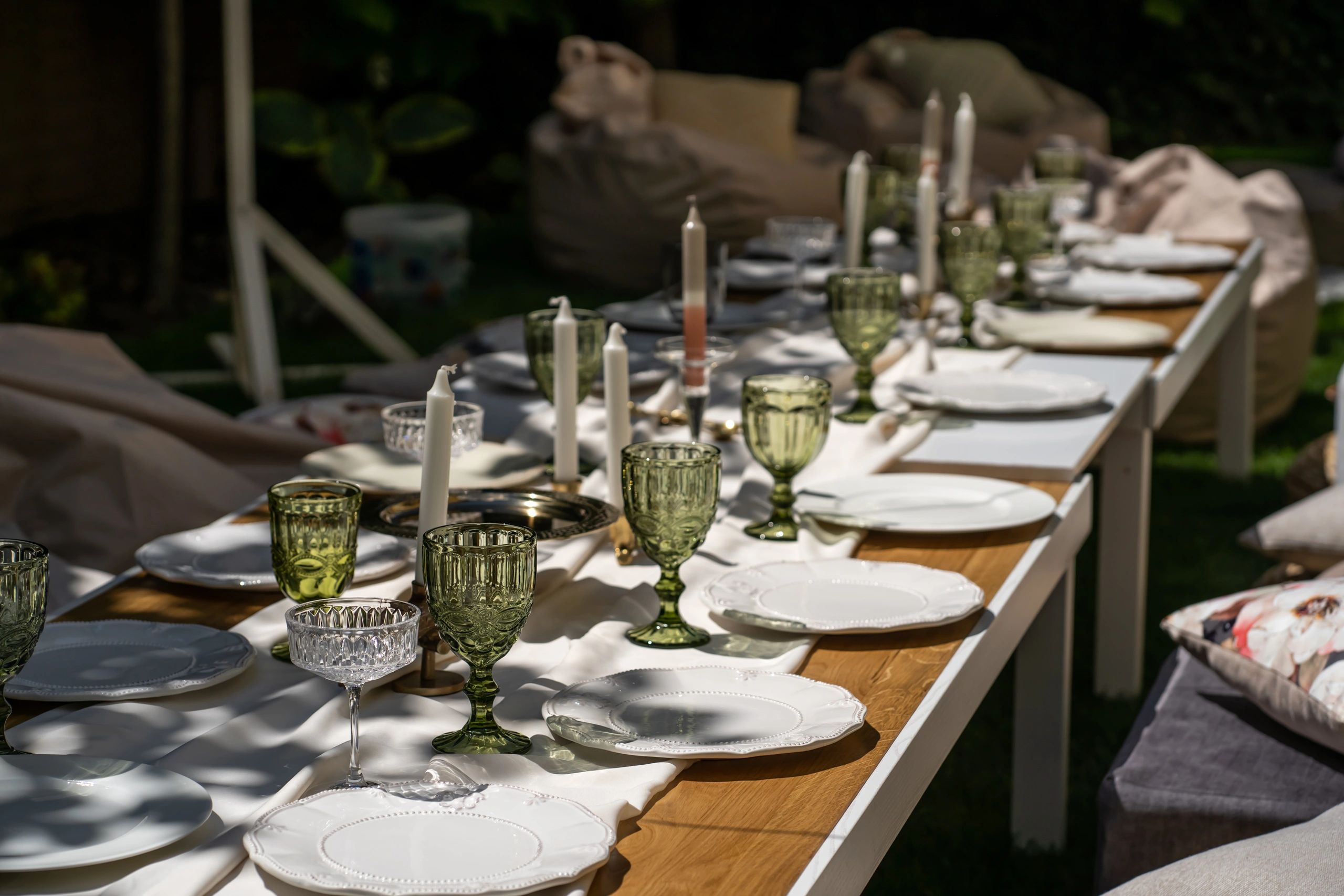Outdoor wooden table set for a special occasion with flowers and glassware